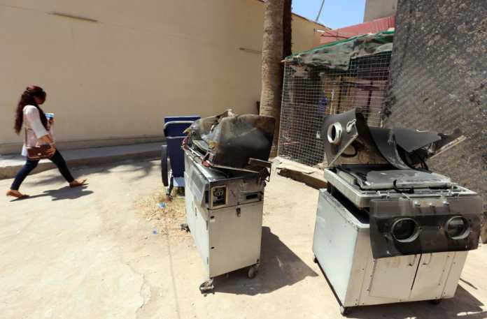 An Iraqi woman walks past burnt incubato