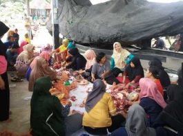 Ibu-ibu istri prajurit bersama masyarakat dalam membagi bagi daging sehingga siap dibagikan, Rabu (22/08/18).