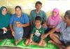 Fauzi (tengah), beserta orang tuanya, Durmawel (tengah), beserta tetangga