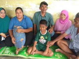 Fauzi (tengah), beserta orang tuanya, Durmawel (tengah), beserta tetangga