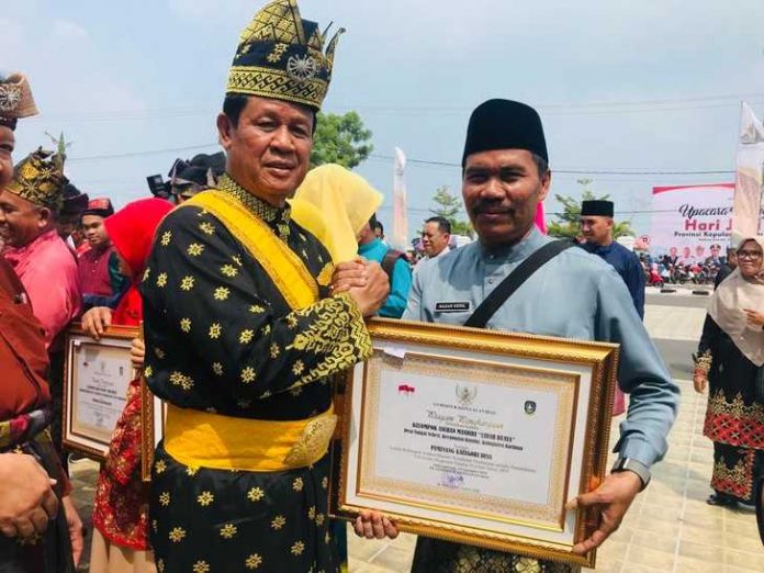 Kades Sei Sebesi, Nazarudin, saat menerima penghargaan dari Plt Gubernur Kepri, Isdianto, pada HUT Kepri ke-17 di Gedung Daerah Tanjungpinang (24/09/19).