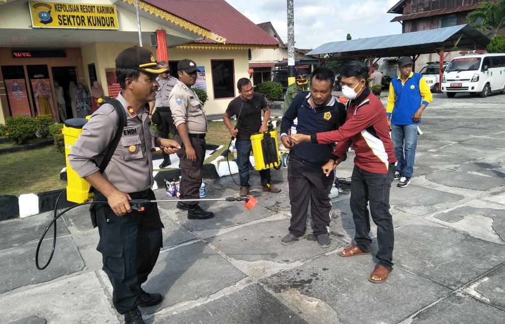 Kapolsek Kundur, Kompol Endi Endarto saat menyemprotkan disinfektan