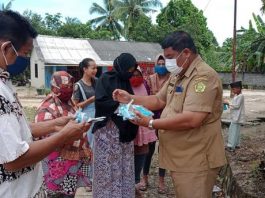 Kades Teluk Radang, Ngadino, saat membagi-bagikan masker kepada warga